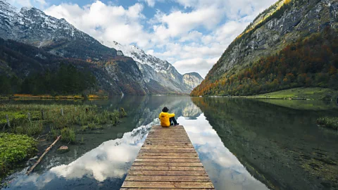 Man sitting on a boat pier at Konigssee lake, Bavaria, Germany