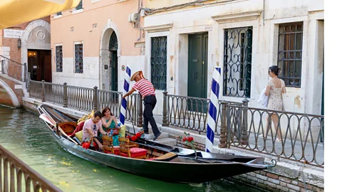 Sandolista and tourists on a sandolo in a Venetian canal (Credit: Carola Cappellari)