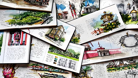 A pile of notebooks with painted sketches of different travel locations (Credit: Alicia Aradilla)