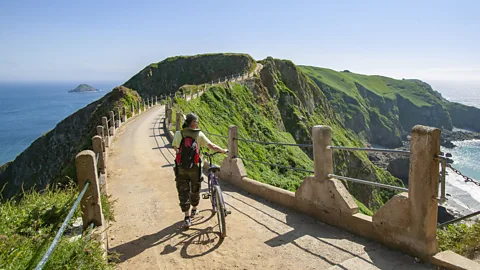 Uwe Moser/Getty Images Woman wheeling a bike on Sark Island