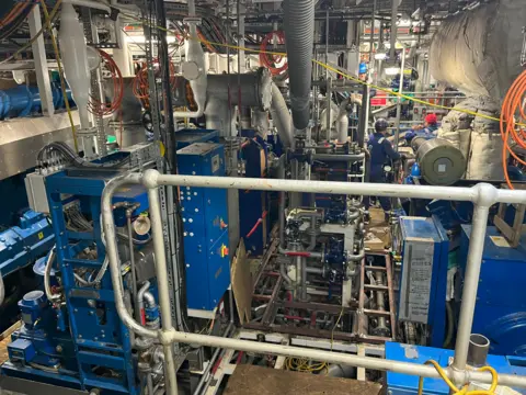 A room full of pipes and blue machinery racks