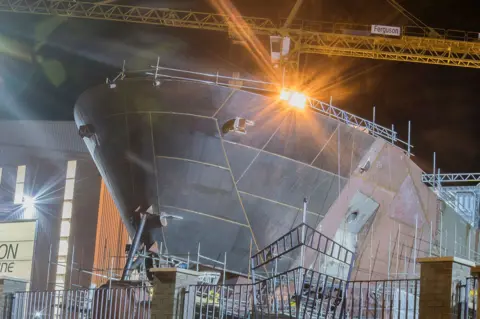 Getty Images A unpainted ship being constructed on a slipway, with a yellow crane in the background