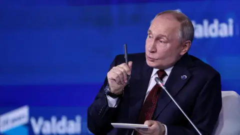 Vladimir Putin speaking holding a pen