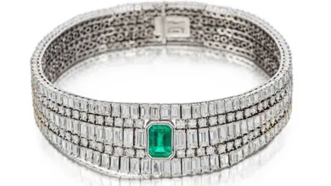 A bracelet or ring that appears to be diamond encrusted, with an emerald