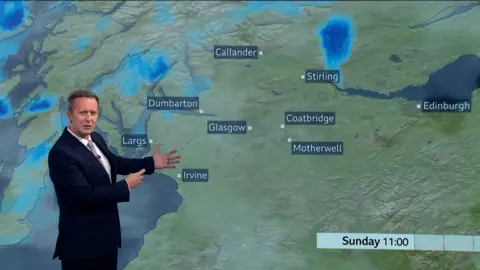 BBC weather presenter Christopher Blanchett in front of weather map showing rain showers