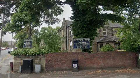 A care home in traditional brickwork stands with signs outside reading "Hunningley Grange".