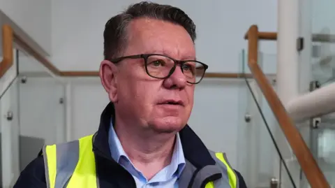 PA Media John Petticrew, a bespectacled man in a fleece and hi vis jacket