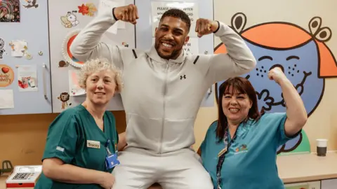 Anthony Joshua pictured with two hospital staff members