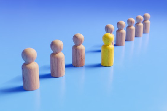 Image of a line of figures with one yellow figure outside the line.