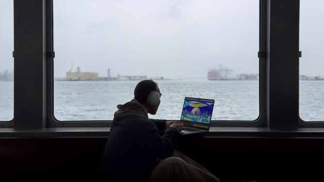 man working on MacBook with view of the water