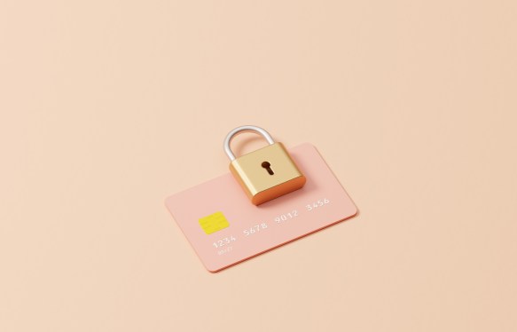 Studio image of a padlock on top of a credit cardchampagne coloured background, could symbolize ideas around encryption, credit card safety, security and passwords