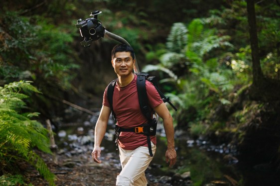 Man hiking in a forest wearing Odyssey camera pack