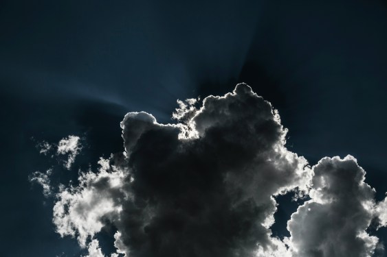 Image of sun shining behind clouds creating a silver lining