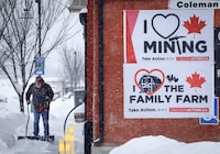 A resident shovels snow near  a sign supporting coal mining on the day the community votes in a plebiscite on whether to support a new coal mine in Crowsnest Pass, Alta., Monday, Nov. 25, 2024.THE CANADIAN PRESS/Jeff McIntosh