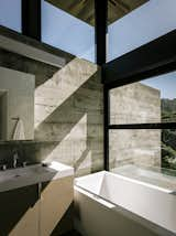 The bathroom in the guest pavilion takes advantage of the passive solar siting. “Detaching the roof from the walls allowed us to bring in light from the top,” notes the architect. The custom vanity holds a Lacava sink; the tub is AquaStone from Aquatica.