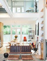 To create a sense of luxury on a budget, the architect ran a thin concrete border along either side of the fireplace flue and flanked it with floor-to-ceiling bookshelves. The second story has two lofts joined by a steel bridge.