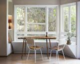 A previously empty space became a nature-infused breakfast nook with a built-in bench seat of wood slats painted white. Arthur Umanoff chairs join a live-edge wood slab table. The lines of the Dansk salt and pepper shaker are mirrored in the vintage lamp, with a cardboard shade found at the Long Beach flea market.