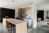 In this kitchen and dining room, architect Bergendy Cooke rethought traditional wood panelling using black pigment-stained veneer. The kitchen has expansive surfaces, including a long, wood-topped kitchen island where the couple cook and entertain, and where the children eat and play. "All of the materials were selected for their integrity and longevity," says Bergendy.