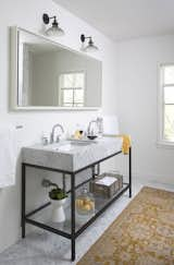 White walls, a luxurious marble double-sink, and an area rug give this bathroom an inviting atmosphere. “The natural light, open spaces, and light color palette make it a great place to wake up in the morning,” Flournoy says of his home. The sink is from Restoration Hardware and the rug is from West Elm.