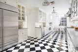 Featuring a timeless black-and-white marble checkerboard floor, the eat-in kitchen receives an abundance of natural light thanks to its huge, six-over-six pane sash window.  