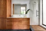 The master bathroom continues many themes found throughout the rest of the home. Dense ipe wood, which clads the exterior and porch columns, was also chosen to line the shower floor, while lightly oiled cherry makes up the bathroom cabinetry.