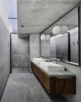 The concrete master bathroom is illuminated by a skylight.