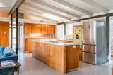 In the kitchen, a new Quartz counter tops the central island. The original cabinetry and pale-yellow Western Holly oven enhance the house's vintage aesthetic, paying homage to the past. 