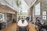 The full-height chimney stack creates a natural division between the dining and living room to the right. A wall of windows caps one end of the space, warming it with natural light and providing picturesque views of the landscape.