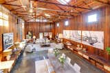 A view down from the loft into the expansive space. Rafters and joists frame the pitched roof, while built-in cabinetry runs down both sides of the open living and dining room.