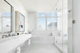 A marble trough sink lines a wall in the bright master bath, complete with an oversized soaking tub and glass walk-in shower.