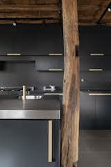 An original timber post stands beside the new sleek cabinetry and stainless-steel countertops.  