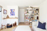 A work by Victoria Fu and Matt Rich hangs across from a book-case by Louis in the family room. The sofa and ottomans are from Room &amp; Board, while the Drum pouf is by Softline and the rug is by West Elm.