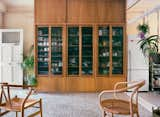 The frosted glass-fronted cabinet in the living room contains shoes and bags on the side by the entrance and tableware nearer to the kitchen.