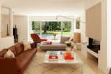 In the living room, a Stricto Sensu sofa by Didier Gomez and a Prado daybed by Christian Werner, both from Cinna, join a marble-topped coffee table by Florence Knoll. The red easy chair and ottoman are from the Platner Collection by Knoll, joined by a stool from La Redoute, a Tulip side table by Eero Saarinen for Knoll, and a pair of PK22 chairs by Poul Kjærholm for Fritz Hansen. The black Potence wall lamp is by Jean Prouvé while the tiles on the floor and above the fireplace are from Living Ceramics.