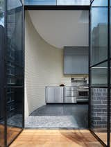 La Paloma Miro brick meets charcoal-colored polished concrete in the kitchen. A stainless-steel backsplash matches the bottom set of cabinetry. 