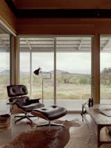 An Eames lounge chair and ottoman anchor the houses's living room, which enjoys floor-to-ceiling views looking north.