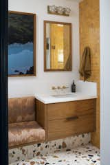 The designer created a teak built-in bench seat for the primary bathroom, where she installed lively Marmoreal flooring, teak vanities, and marigold Zellige shower tile.