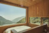 The sleeping area, outfitted with a California king-size bed with a built-in headboard made from Baltic birch, showcases expansive views of the mountain landscape, connecting guests to nature.