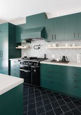 The cabinets were custom designed by Síol Studios and painted Deep Jungle—a bold shade of green from Pratt & Lambert. The backsplash features hand-painted terra cotta tiles by Walker Zanger. The oven range is from AGA Countertops. The floor is finished with hand-painted arabesque terra cotta tiles from Tabarka Studios.