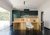 The insertion of a NanaWall opens the kitchen to the backyard and repositions the kitchen as the center of the home. The black chandelier above the kitchen island is Mobile #3 by Michael Anastassiades. 