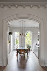 The new arched window brings light and views into the open-plan kitchen and dining area. Five colorful, geometric pendants designed by Jula Jessen for Schneid's Junit collection hangs over the dining table. 