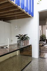 "The planter box was an excuse and a solution to integrate the electric plugs on the counter," shared Otten. The stunning slab of pink marble which serves as the island's countertop is the result of a trade between the client, an artist, who traded a work of art for it with the art-collecting owner of Vandeweghe, the marble company, where the beautiful slab of pink marble is from. Brass cabinet doors reflect the terrazzo flooring from Bomarbre. 