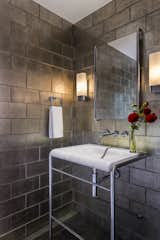 The powder room in a renovated 1957 midcentury modern home in Portland takes on a moody vibe with textured, irridescent floor-to-ceiling tiles but stays sleek with streamlined fixtures in polished nickel and marble.