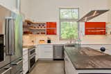 The white subway-tiled backsplash and open shelving  make the kitchen look brighter and more spacious. The wrap-over counter top on the island looks like weathered steel but it's actually Dekton®, a composite material.