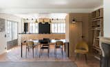 The open kitchen faces a wall of above-counter windows that let in plenty of light. The dining table maintains the material palette of wood and black.