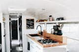 In the kitchen, white cabinets are combined with black accents and a butcher block countertop, including the sink basin and faucet. Windows at the counter bring in lots of natural light.

