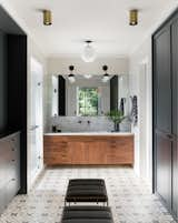 In the master bathroom, the Clé Tile floor, custom walnut vanity, and marble counter fashion a luxe retreat. Lighting is from a mix of manufacturers, including One Forty Three, Rejuvenation, Cedar & Moss, and Atelier de Troupe. The faucet is from Watermark.

