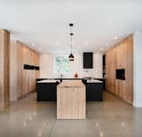 The kitchen counters and backsplash are from the Inalco Touché ceramic collection by Italbec. Base cabinets are lacquered in matte black and combined with natural white oak units, made bespoke by Ébénisterie Gaston Chouinard. 