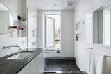 Now, a generous shower has a custom step-through window from Starr Windows & Doors to access the roof deck. Floors are Nero Marquina hexagon tile, and the custom vanity has a marble counter. A Kohler Purist faucet and Cedar & Moss sconce complete the look.