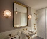 The revamped bathroom features Ann Sacks Lume glass mosaic tile on the walls and Artistic Tile’s Belgium Blue Matte on the floor. A Restoration Hardware Varese brass-and-bronze mirror hangs above the Calacatta gold marble and unlacquered brass vanity by Kallista.